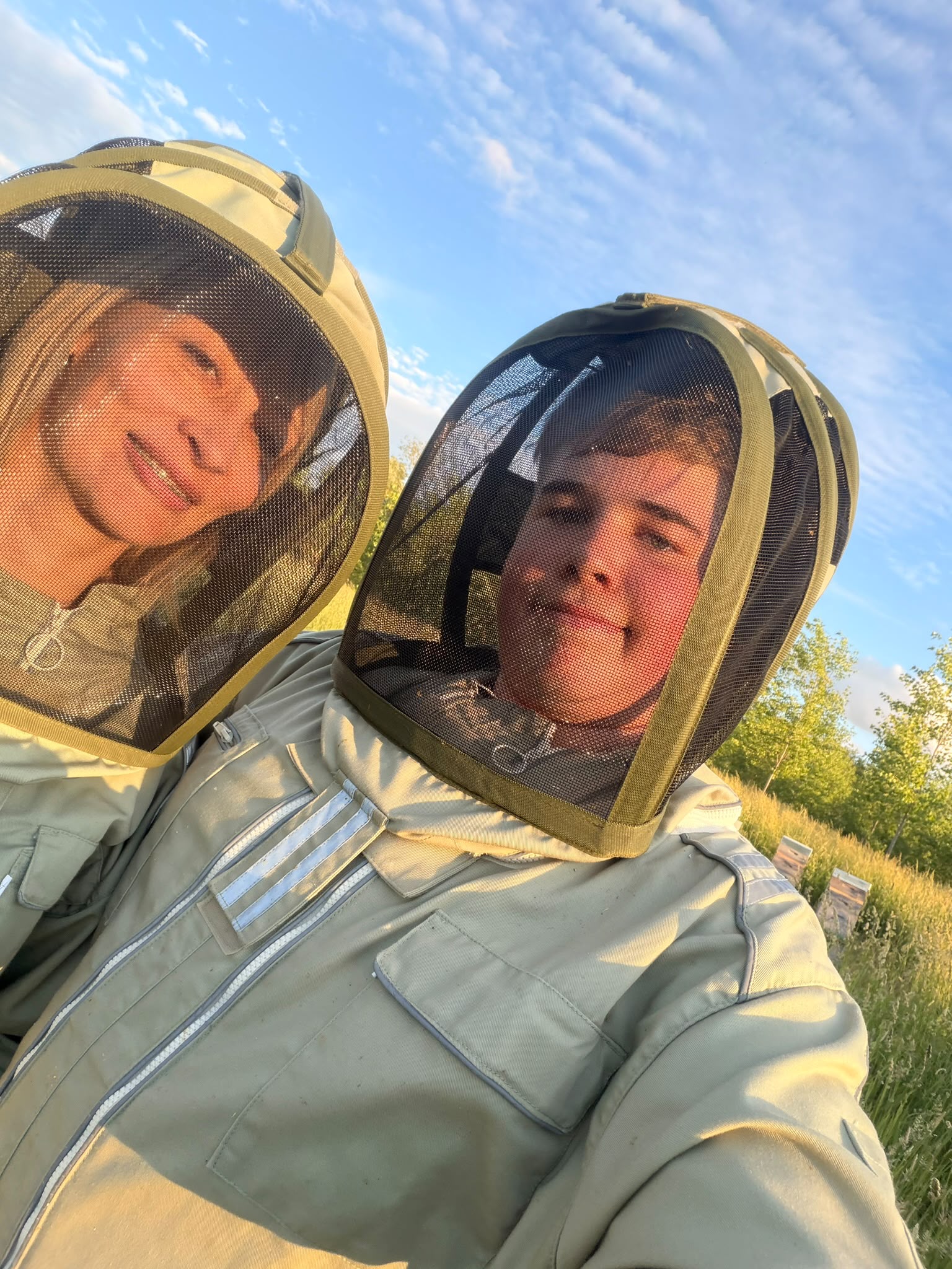 Deux apiculteurs en tenue au rucher, au soleil couchant